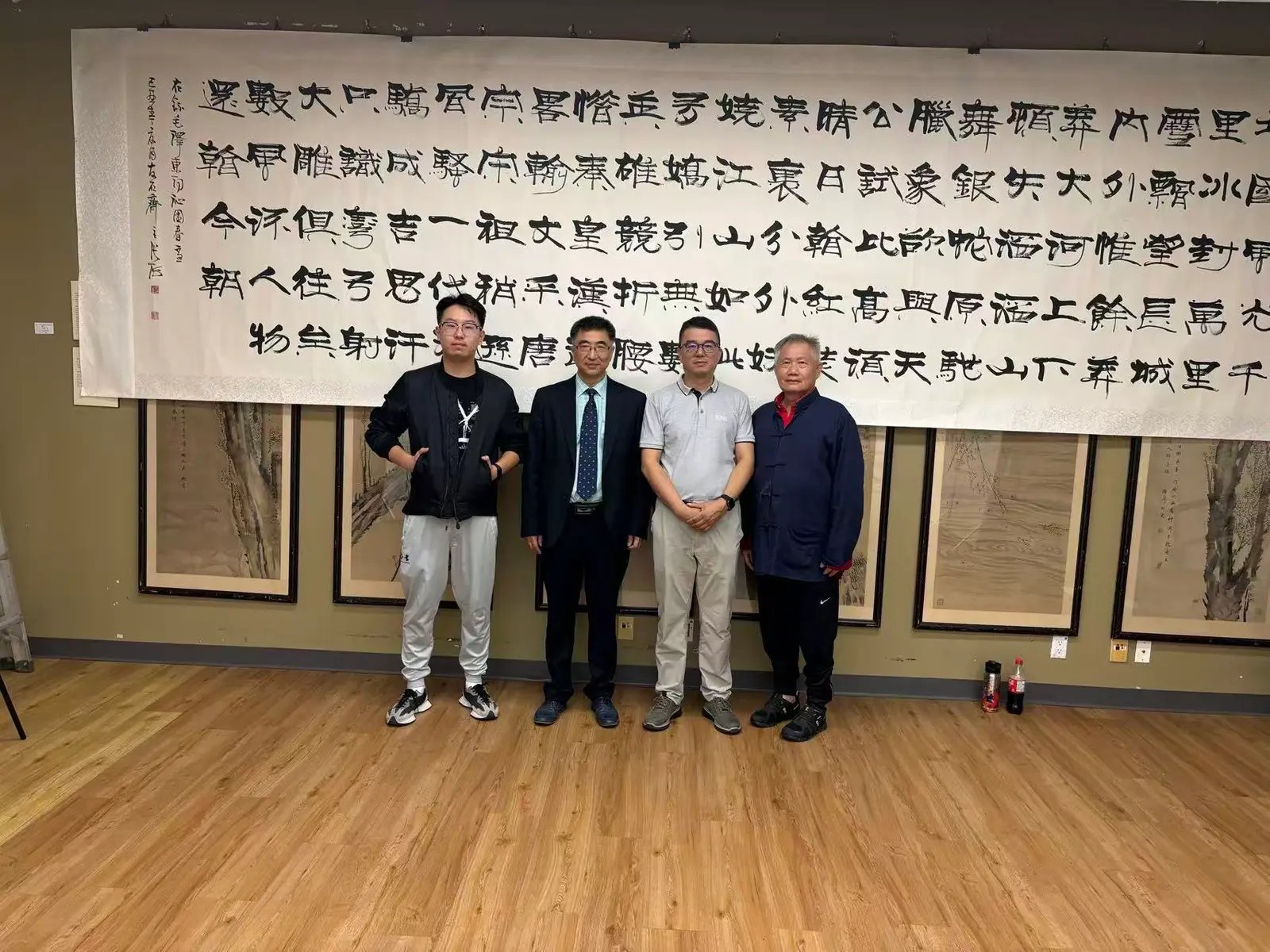 Members before a large clerical-script calligraphy work